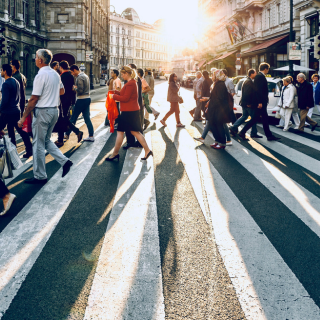 photographie d'une foule de personnes qui traversent un passage pour piétons au couché du soleil